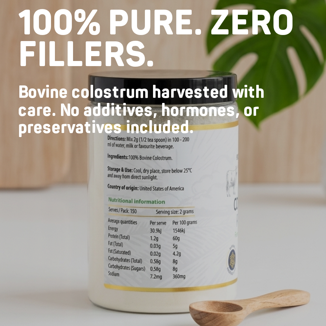 Bovine colostrum powder container with text highlighting purity and ingredient details, wooden spoon on a light surface.